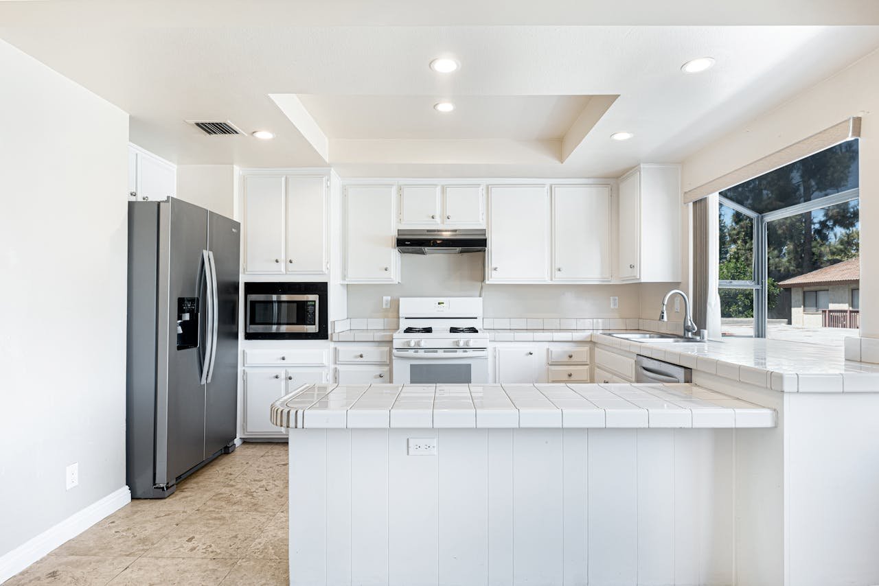 Services Spacious white kitchen featuring stainless steel appliances and contemporary design for comfortable living.