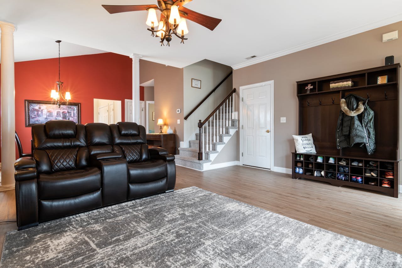 About Spacious living area featuring black leather couches, a chandelier, and modern interior design elements.