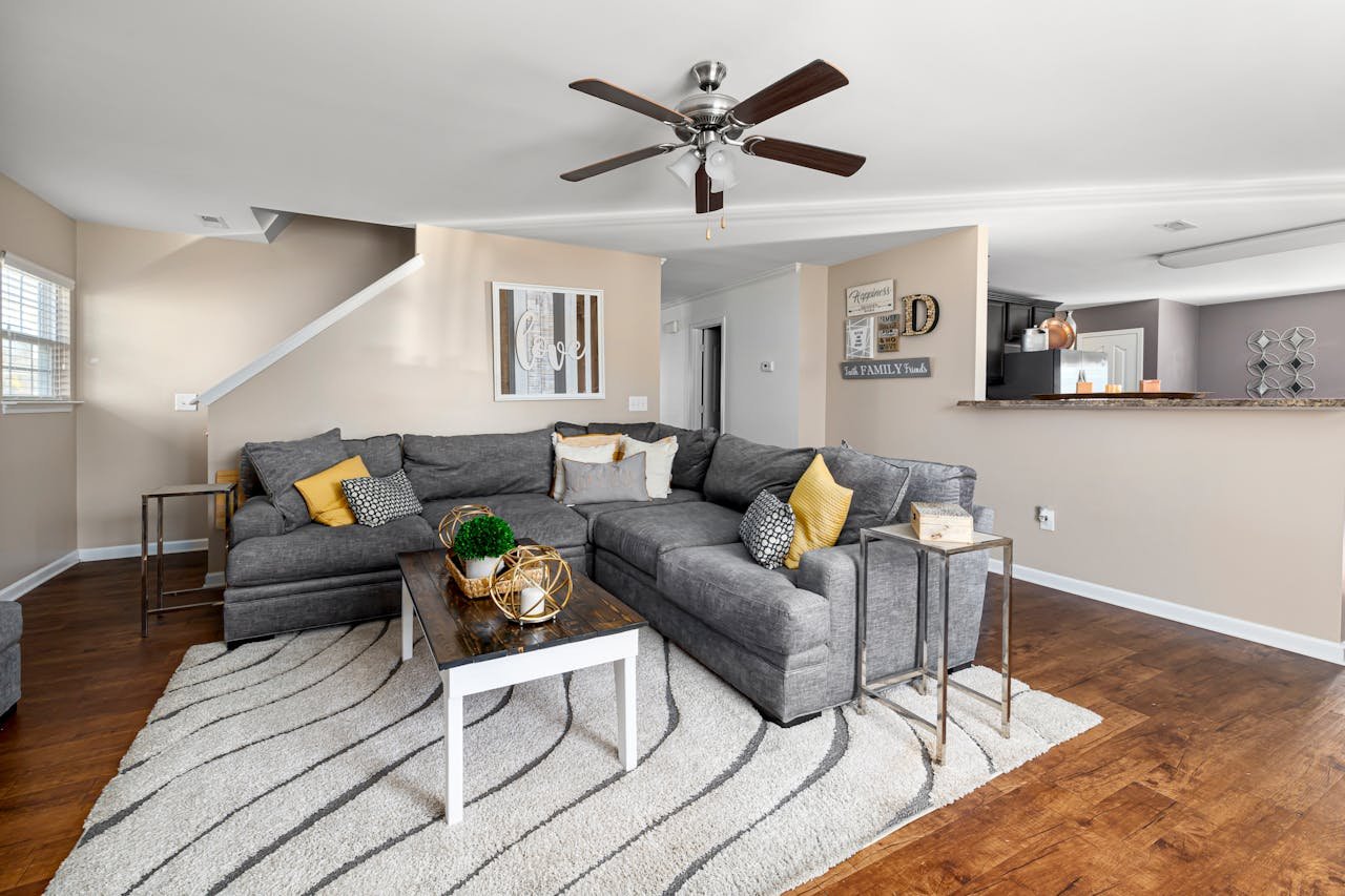 Services Stylish living room featuring a gray sectional sofa, wooden flooring, and decor accents.